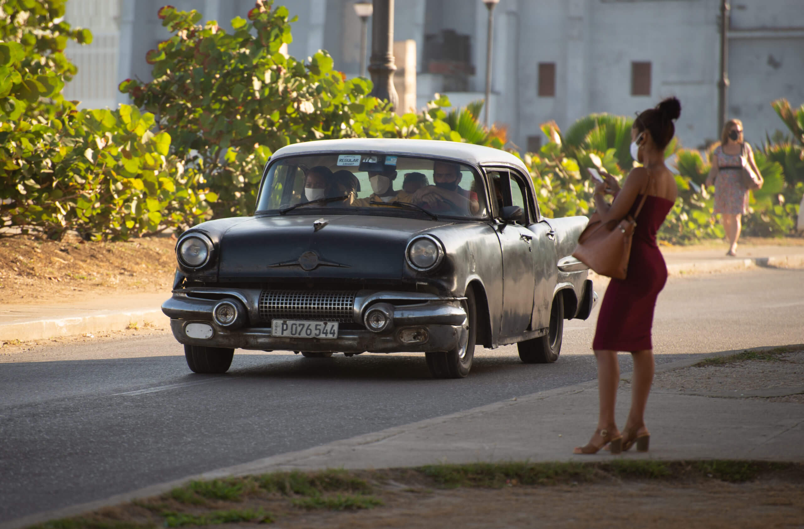 A woman waits to cross a busy street in the Habana Centro district. © 2022 John D. Elliott • www.TheHumanPulse.com